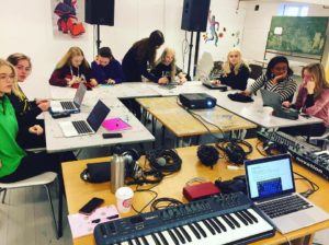 8 deltakere sitter rundt ett C-formet bord foran egne laptops og jobber med musikkproduksjon